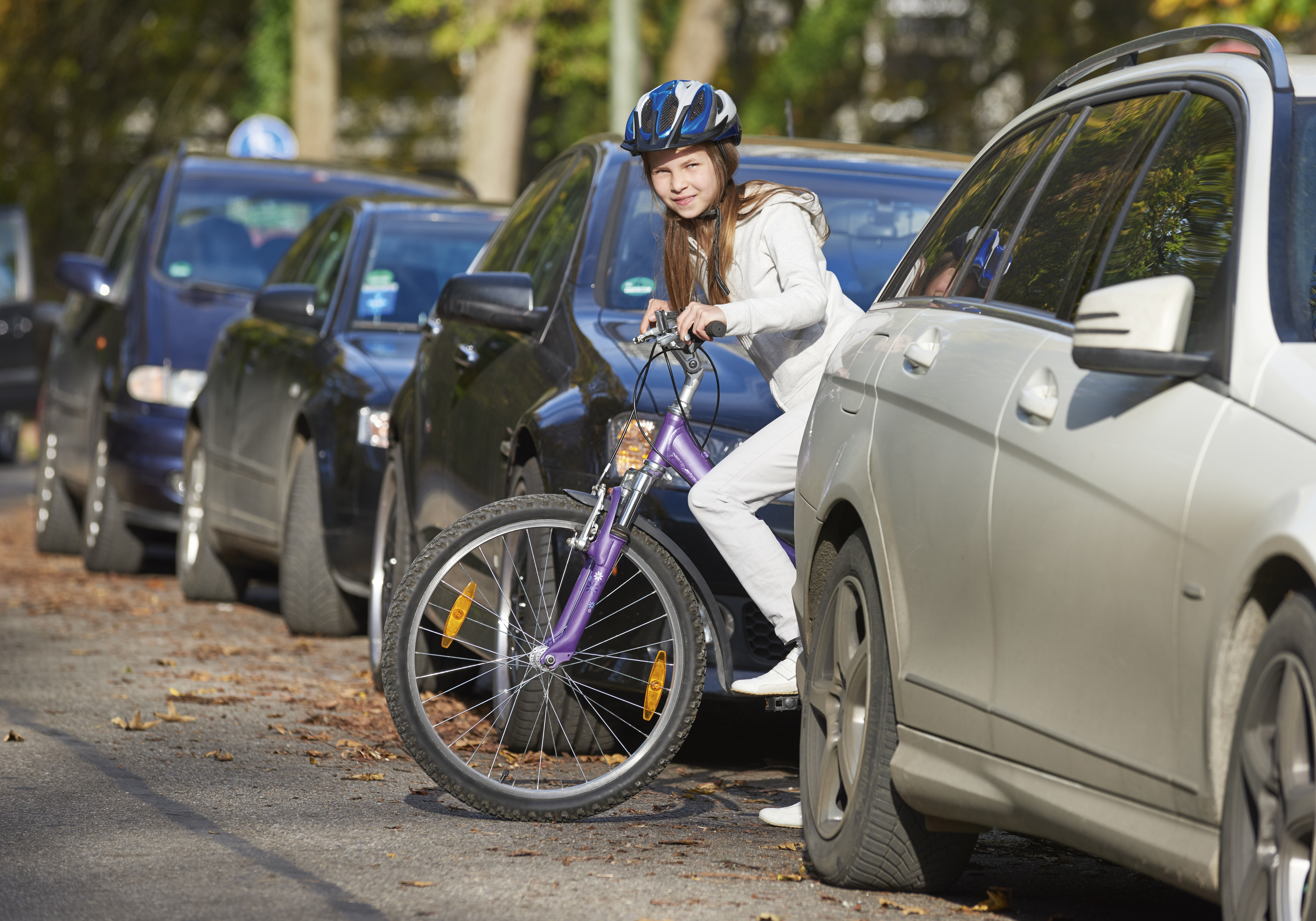 Mädchen mit Fahrrad zwischen parkenden Autos